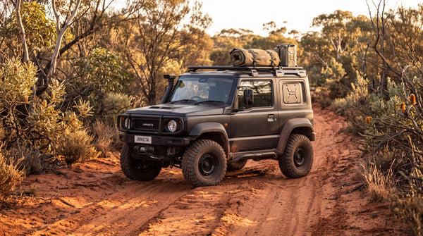 Suzuki Jimny fitted with a Urnieta bull bar, snorkel and roof rack on a red dirt track in the bush